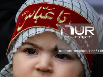 A Shiite Muslim child is looking on during a religious procession in Srinagar, Jammu and Kashmir, on August 01, 2024. (