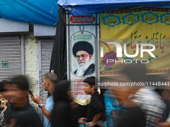 Shiite Muslim mourners are walking past a flag showing supreme leader, Ayatollah Ali Khamenei, during a religious procession in Srinagar, Ja...