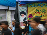 Shiite Muslim mourners are walking past a flag showing supreme leader, Ayatollah Ali Khamenei, during a religious procession in Srinagar, Ja...