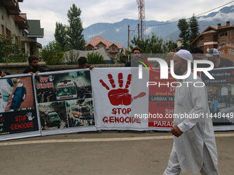 A man is walking past Kashmiri Shiite Muslims who are holding banners during a religious procession on the 25th day of the Islamic month of...