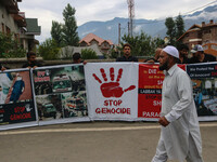 A man is walking past Kashmiri Shiite Muslims who are holding banners during a religious procession on the 25th day of the Islamic month of...