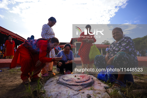 Nepali Hindu devotees are performing a ritual at the spot where the chariot of the Red God, Rato Macchindranath, is being rested after touri...