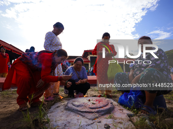 Nepali Hindu devotees are performing a ritual at the spot where the chariot of the Red God, Rato Macchindranath, is being rested after touri...