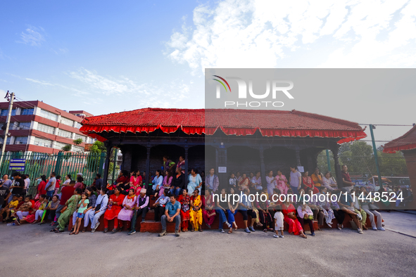 Nepali Hindu devotees are sitting on a Falcha, a public rest place, to observe the procession of the Red God, Rato Macchindranath's final to...