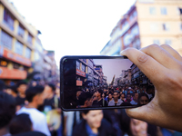 A Nepali Hindu devotee is capturing the procession of the Red God, Rato Macchindranath, wading through a sea of devotees as it approaches th...