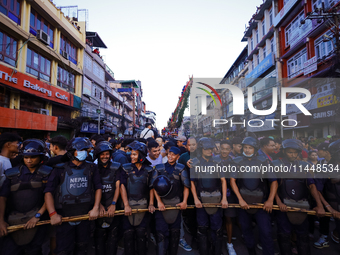 Nepal Police personnel are creating a human barricade, escorting the devotees and the chariot of the Red God, Rato Macchindranath, as it app...