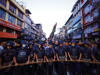 Nepal Police personnel are creating a human barricade, escorting the devotees and the chariot of the Red God, Rato Macchindranath, as it app...