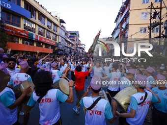 Nepali devotees are playing traditional musical instruments as the procession of the Red God, Rato Macchindranath, is approaching the final...