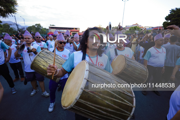 Nepali devotees are playing traditional musical instruments as the procession of the Red God, Rato Macchindranath, is approaching the final...