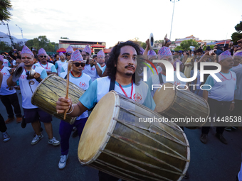 Nepali devotees are playing traditional musical instruments as the procession of the Red God, Rato Macchindranath, is approaching the final...