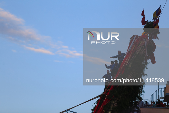 Nepali devotees are climbing up the chariot of the Red God, Rato Macchindranath, as it approaches the final tour of the city, wrapping up th...