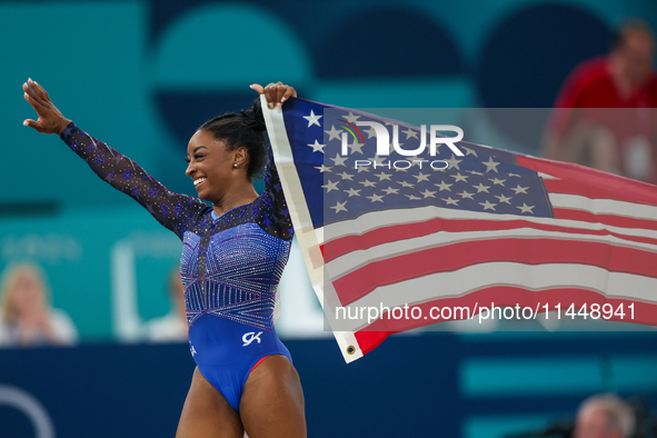 Gold medalist and winner Simone Biles of USA celebrates victory with the USA flag while the women's final all-round competition on day six o...