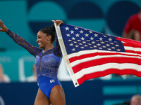 Gold medalist and winner Simone Biles of USA celebrates victory with the USA flag while the women's final all-round competition on day six o...