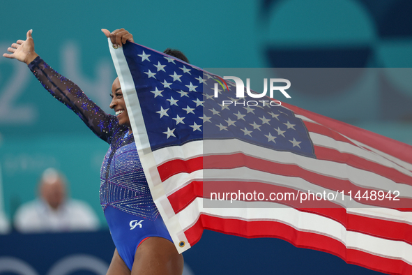 Gold medalist and winner Simone Biles of USA celebrates victory with the USA flag while the women's final all-round competition on day six o...