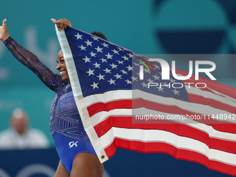 Gold medalist and winner Simone Biles of USA celebrates victory with the USA flag while the women's final all-round competition on day six o...