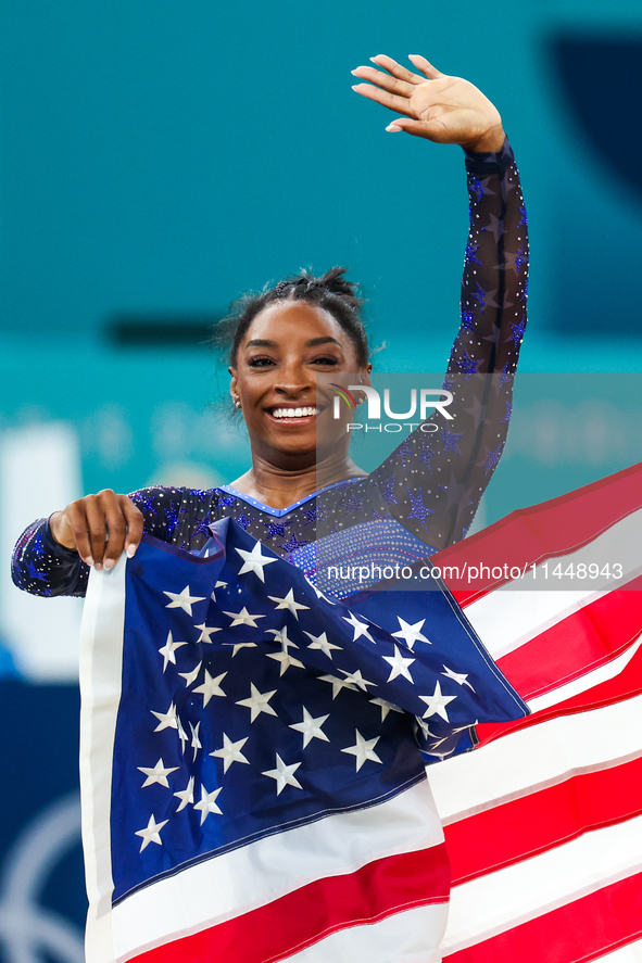 Gold medalist and winner Simone Biles of USA celebrates victory with the USA flag while the women's final all-round competition on day six o...