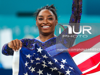 Gold medalist and winner Simone Biles of USA celebrates victory with the USA flag while the women's final all-round competition on day six o...