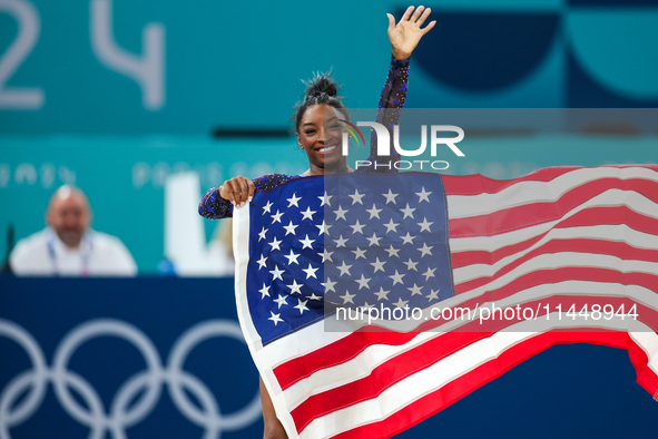 Gold medalist and winner Simone Biles of USA celebrates victory with the USA flag while the women's final all-round competition on day six o...