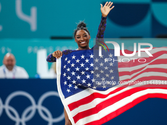 Gold medalist and winner Simone Biles of USA celebrates victory with the USA flag while the women's final all-round competition on day six o...