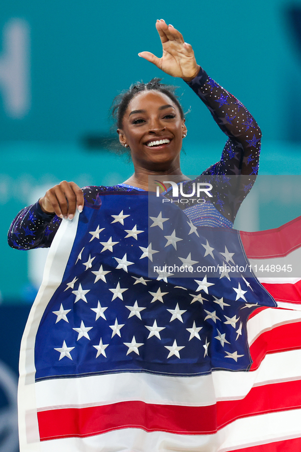 Gold medalist and winner Simone Biles of USA celebrates victory with the USA flag while the women's final all-round competition on day six o...