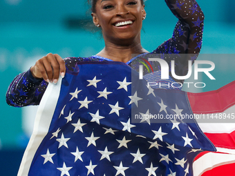 Gold medalist and winner Simone Biles of USA celebrates victory with the USA flag while the women's final all-round competition on day six o...