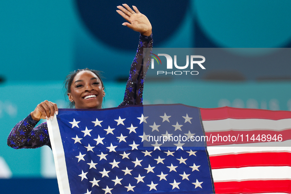 Gold medalist and winner Simone Biles of USA celebrates victory with the USA flag while the women's final all-round competition on day six o...