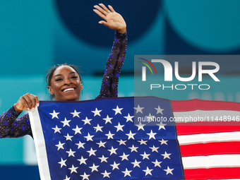 Gold medalist and winner Simone Biles of USA celebrates victory with the USA flag while the women's final all-round competition on day six o...