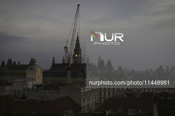 The crane operates near the Vienna City Hall during the evening in Vienna. Austria, Thursday, August 1, 2024. 