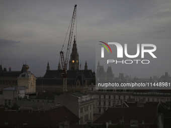 The crane operates near the Vienna City Hall during the evening in Vienna. Austria, Thursday, August 1, 2024. (