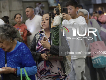 A woman is holding an image of St. Jude Thaddeus at the Church of San Hipolito in Mexico City, Mexico, on August 1, 2024 where dozens of peo...