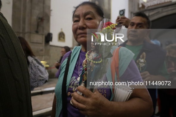 A woman is holding an image of St. Jude Thaddeus at the Church of San Hipolito in Mexico City, Mexico, on August 1, 2024 where dozens of peo...