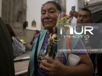 A woman is holding an image of St. Jude Thaddeus at the Church of San Hipolito in Mexico City, Mexico, on August 1, 2024 where dozens of peo...