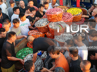 Workers are loading and unloading swimming crabs at the dock of Zhoushan International Aquatic City in Zhoushan, China, on August 2, 2024. (