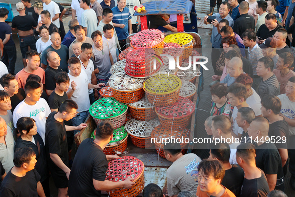 Workers are loading and unloading swimming crabs at the dock of Zhoushan International Aquatic City in Zhoushan, China, on August 2, 2024. 