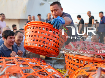 Workers are loading and unloading swimming crabs at the dock of Zhoushan International Aquatic City in Zhoushan, China, on August 2, 2024. (