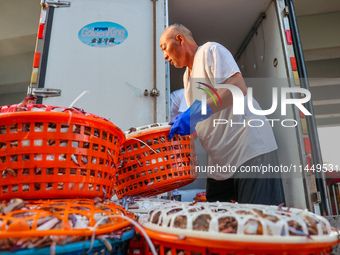 Workers are loading and unloading swimming crabs at the dock of Zhoushan International Aquatic City in Zhoushan, China, on August 2, 2024. (