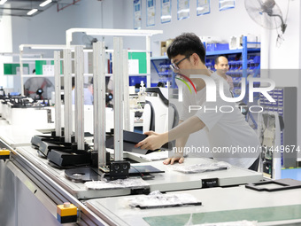 A staff member is assembling intelligent robots at a production line in Fuzhou, China, on August 1, 2024. (