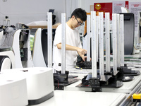 A staff member is assembling intelligent robots at a production line in Fuzhou, China, on August 1, 2024. (