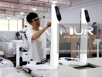 A staff member is assembling intelligent robots at a production line in Fuzhou, China, on August 1, 2024. (