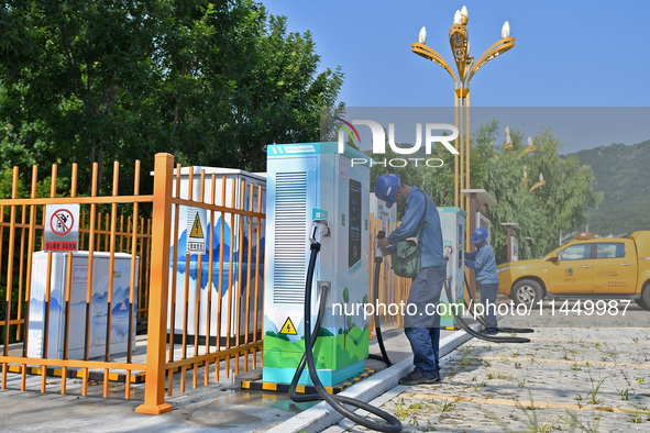 Staff members of the power supply department are checking the operation of electric vehicle charging pile facilities in Dukou village, Yanta...