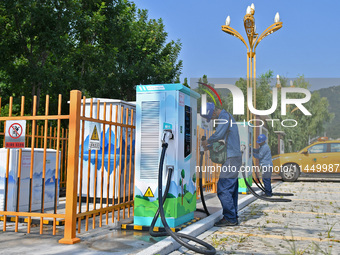 Staff members of the power supply department are checking the operation of electric vehicle charging pile facilities in Dukou village, Yanta...