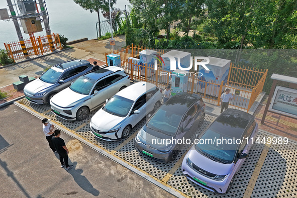 A car owner is using a charging pile to charge an electric vehicle in Dukou village, Yantai, China, on August 2, 2024. 