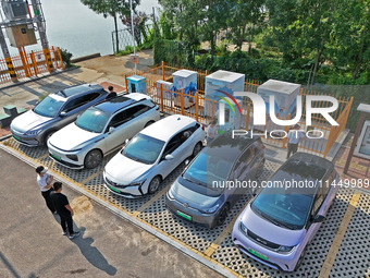 A car owner is using a charging pile to charge an electric vehicle in Dukou village, Yantai, China, on August 2, 2024. (