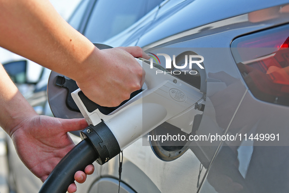 A car owner is using a charging pile to charge an electric vehicle in Dukou village, Yantai, China, on August 2, 2024. 