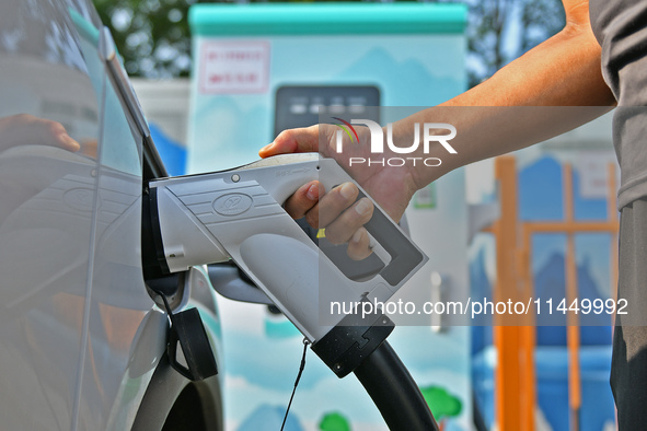 A car owner is using a charging pile to charge an electric vehicle in Dukou village, Yantai, China, on August 2, 2024. 