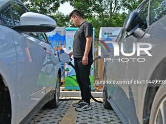 A car owner is using a charging pile to charge an electric vehicle in Dukou village, Yantai, China, on August 2, 2024. (