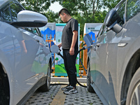 A car owner is using a charging pile to charge an electric vehicle in Dukou village, Yantai, China, on August 2, 2024. (