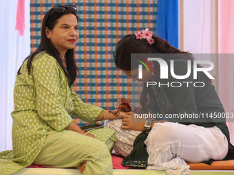 Nepali Hindu women are painting their palms with Heena, commonly called ''mehendi,'' at a fair in Kathmandu, Nepal, on August 2, 2024, as pa...