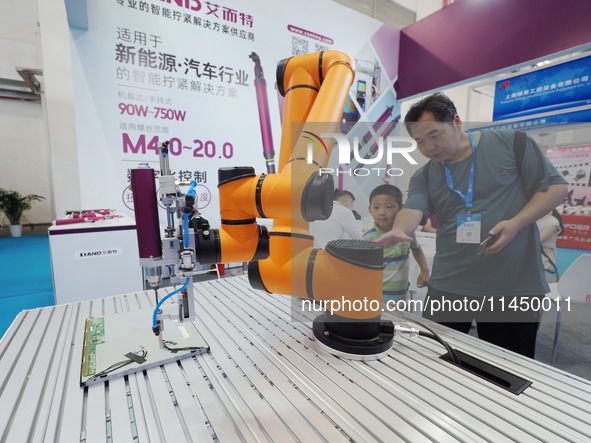 Visitors are visiting a ''six-axis industrial robot'' at the 13th Beijing International Automobile Manufacturing Expo 2024 in Beijing, China...