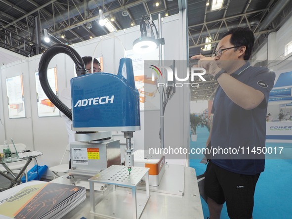 Visitors are visiting an ''automatic grasping robot'' at the 13th Beijing International Automobile Manufacturing Expo 2024 in Beijing, China...